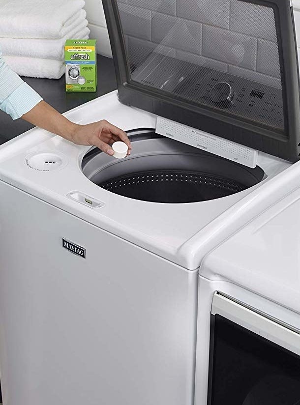 Small tab of cleaner being dropped into washer
