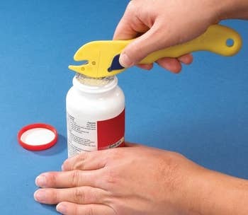 hand using opener to open medicine bottle