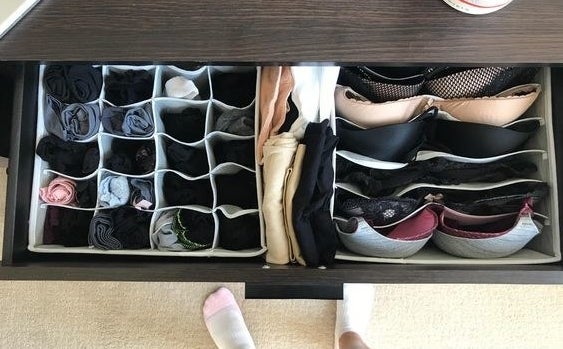 a reviewer photo of open drawer with the organizer bins inside filled with clothes 