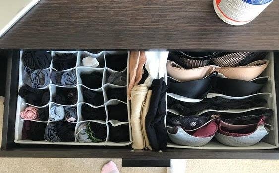 a reviewer photo of open drawer with the organizer bins inside filled with clothes 