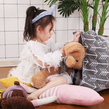 child putting stuffed animals inside bean bag 