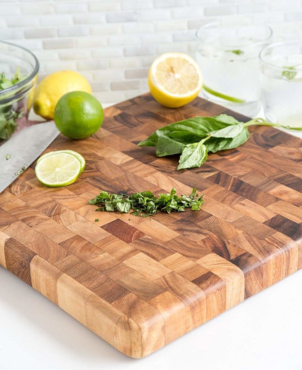 Patchwork wood cutting board with chopped herbs on it 