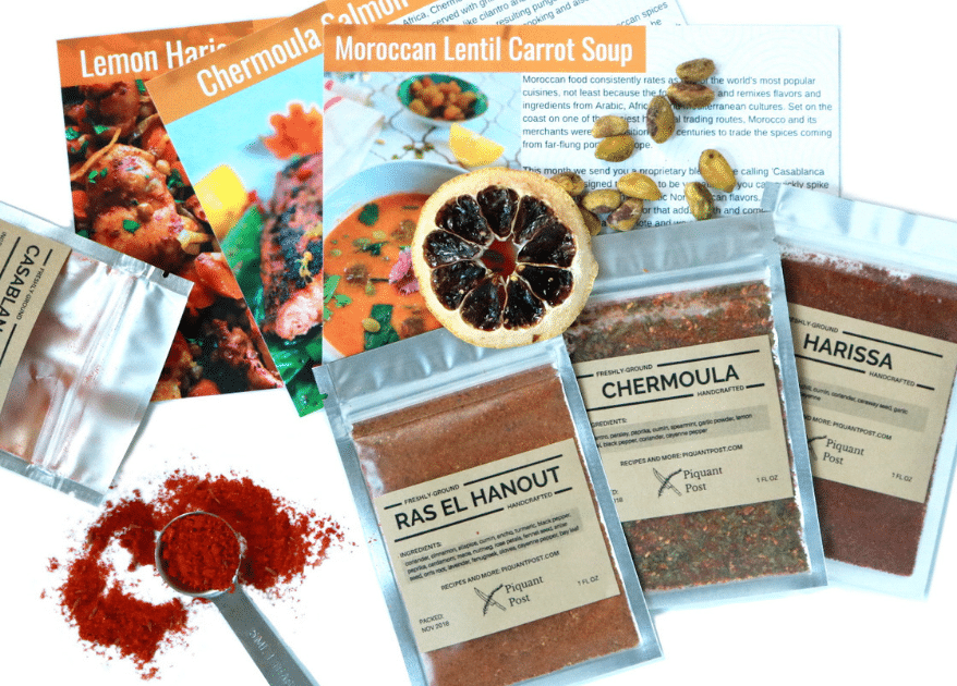 three recipe cards and bags of ras el hanout, chermoula, and harissa powdered spices
