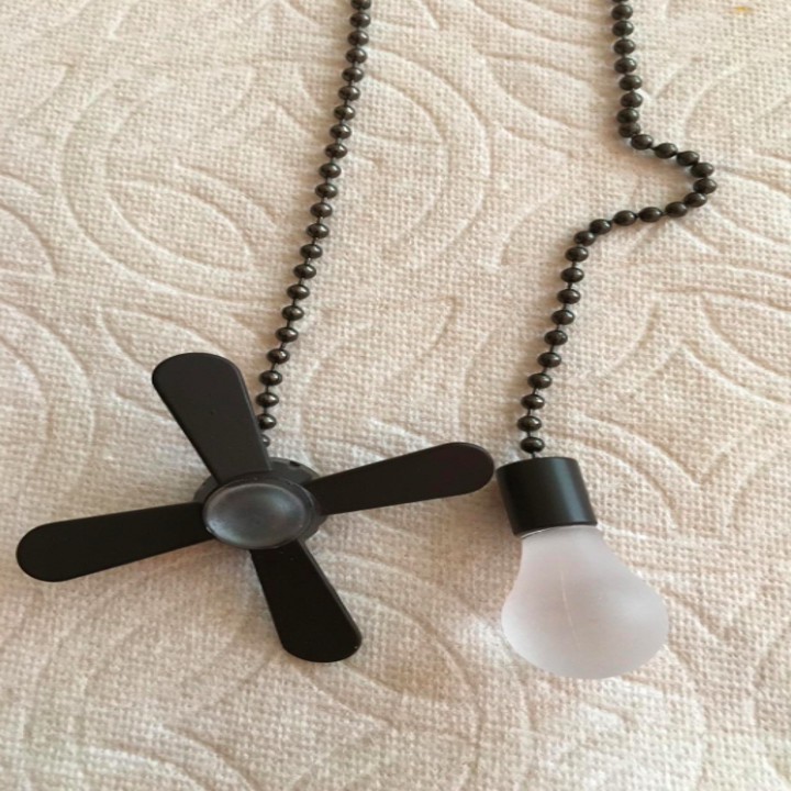 a close up of the pull chains with one side being a tiny fan and one side being a tiny bulb