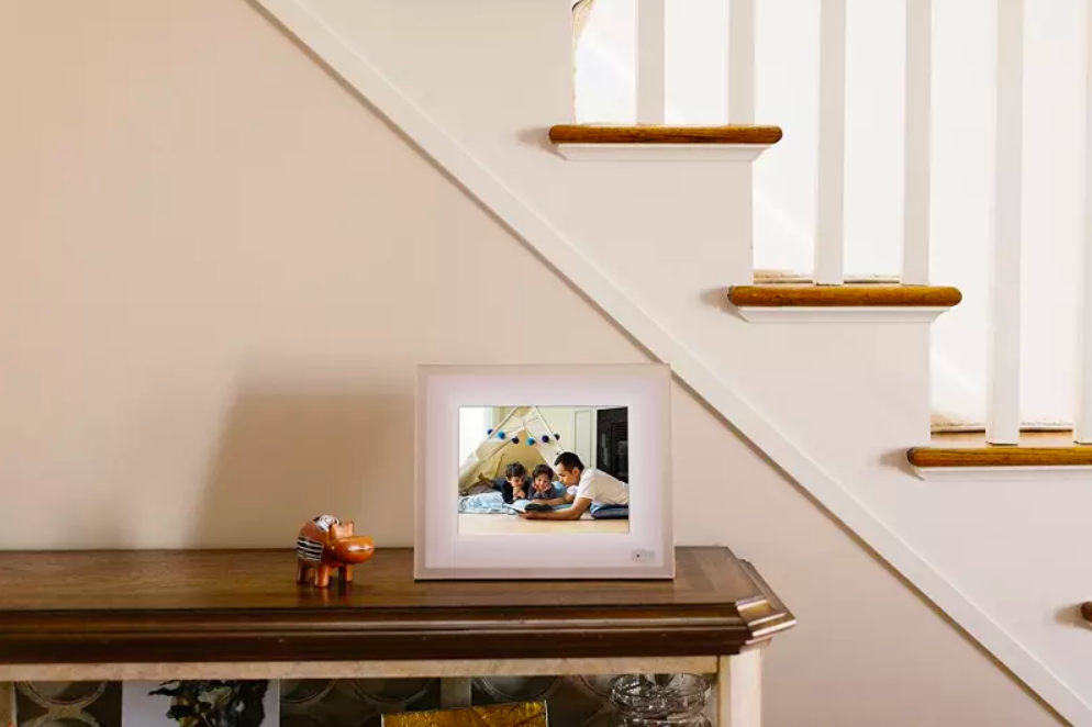 A lifestyle shot of the picture frame on an entryway table, showing an image of a family of three