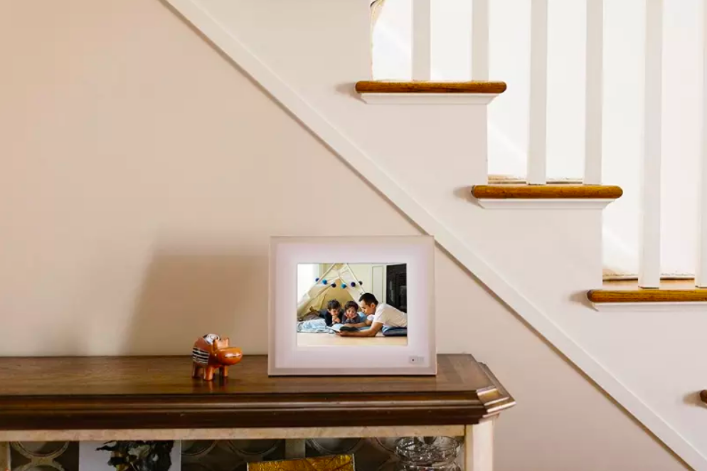 A lifestyle shot of the picture frame on an entryway table, showing an image of a family of three 