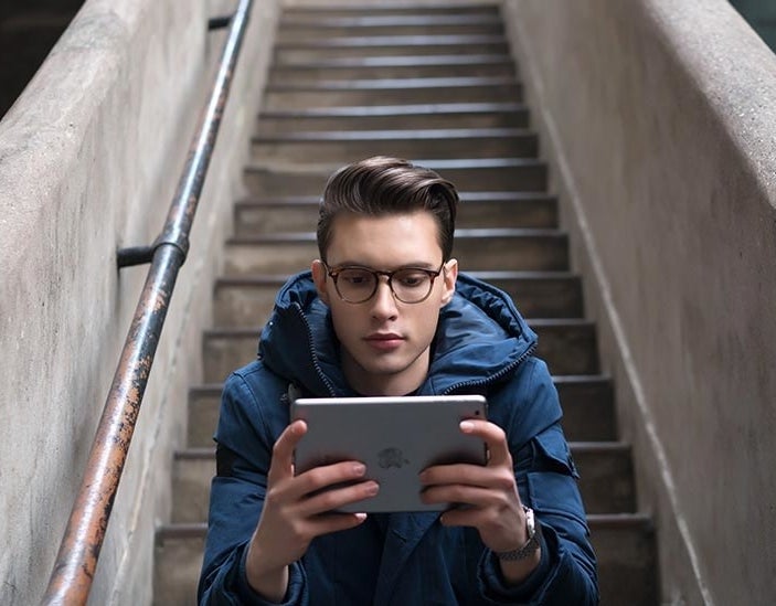 Model wearing glasses holding an iPad 