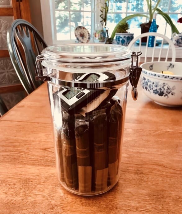 Reviewer photo of the jar humidor holding multiple cigars and a hydrometer