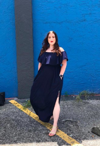 Reviewer wearing the off-the-shoulder ruffle maxi dress in navy blue with a slit up the side.