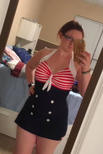 reviewer in high-waist halter swim dress with buttons and a tie at the bust, bust is red and white stripe and bottom is navy with white buttons