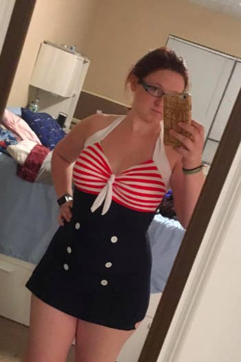 reviewer in high-waist halter swim dress with buttons and a tie at the bust, bust is red and white stripe and bottom is navy with white buttons