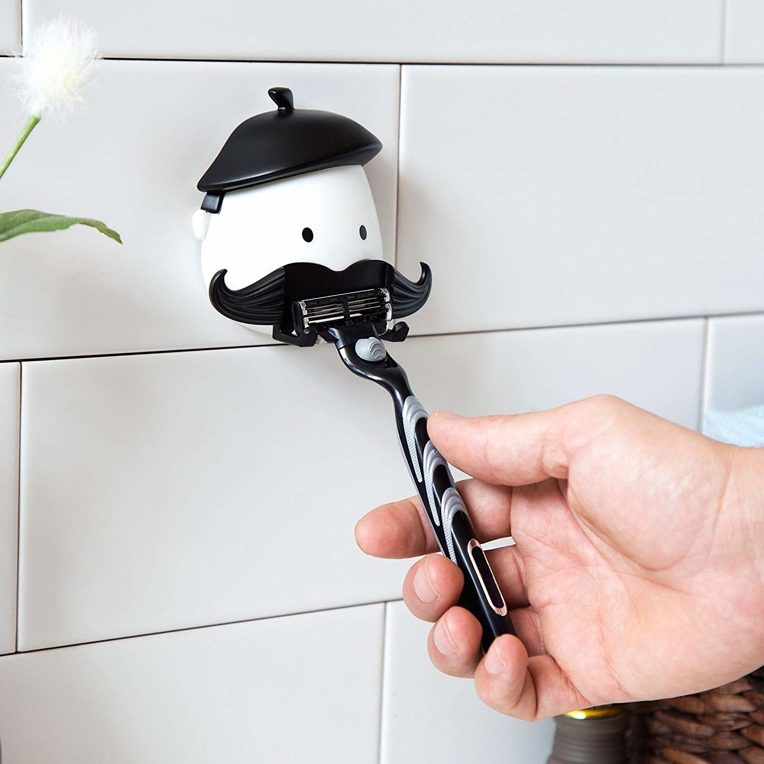 black and white character with mustache that has bars for a razor to hang on. it sticks to shower wall