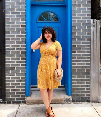 Reviewer wearing the v-neck short-sleeved dress in yellow with small white flowers all over it.