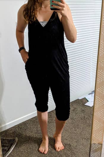 A reviewer wearing the V-neck, spaghetti strap jumpsuit in black with a bandeau underneath