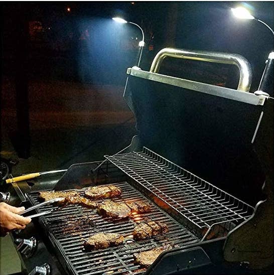 a model grills at night with two lights connected to the top of the grill