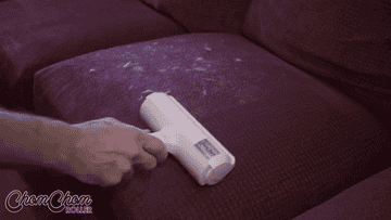 Gif of the roller removing white pet hair from couch cushions