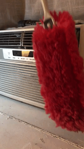 Gif of the duster being used to remove dust from the front of a BuzzFeed editor's air conditioner unit