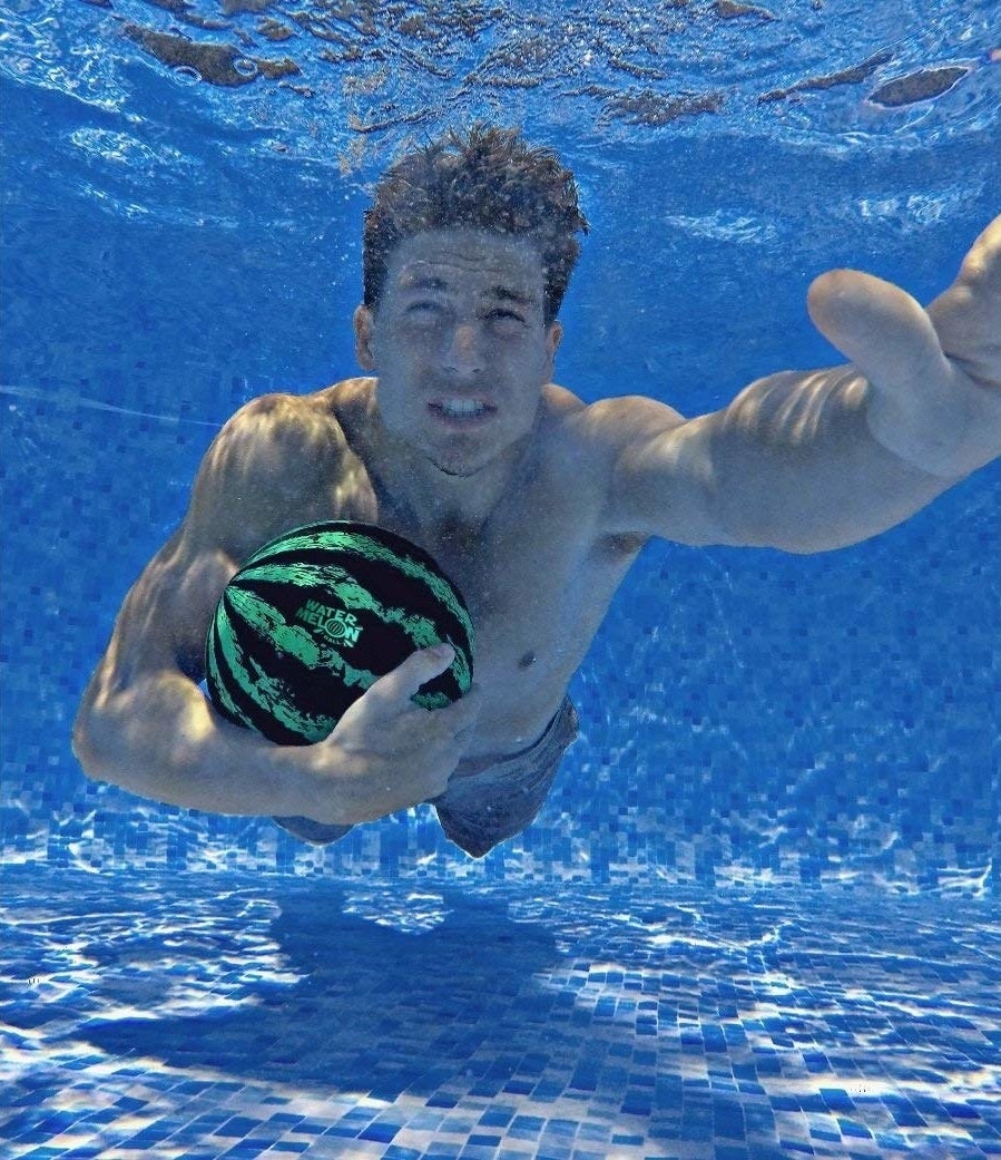 model swims underwater holding watermelon ball 
