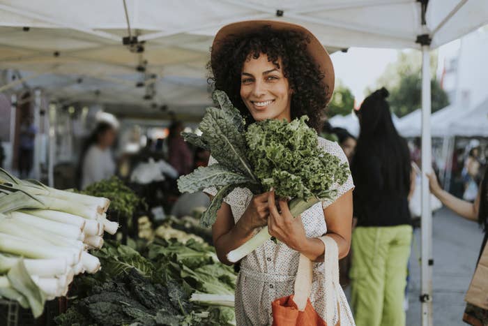Woman holding a bunch of kale at a farmer&#x27;s market