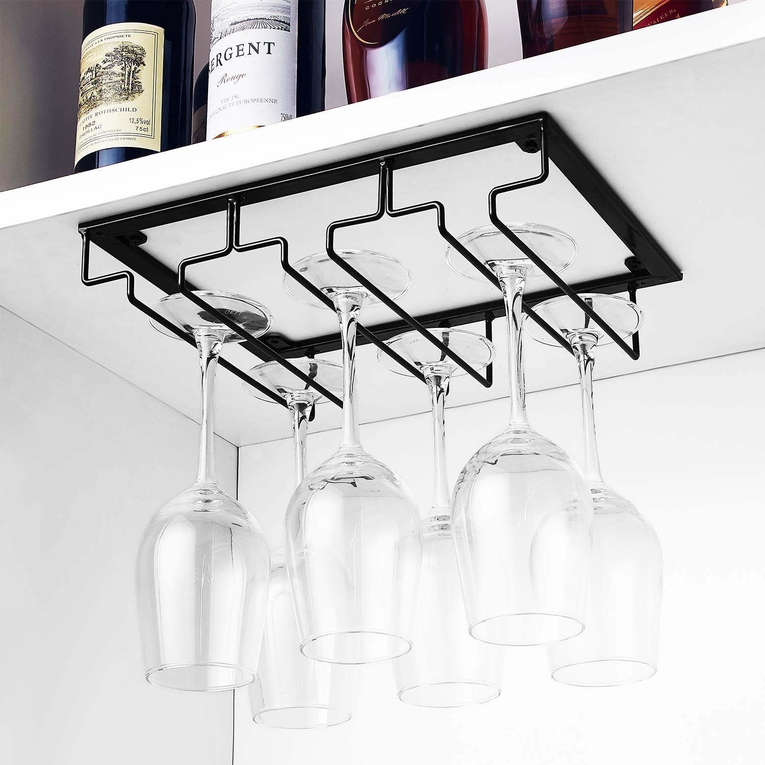 The black metal rack hanging under a cabinet, with six wine glasses hanging upside-down 