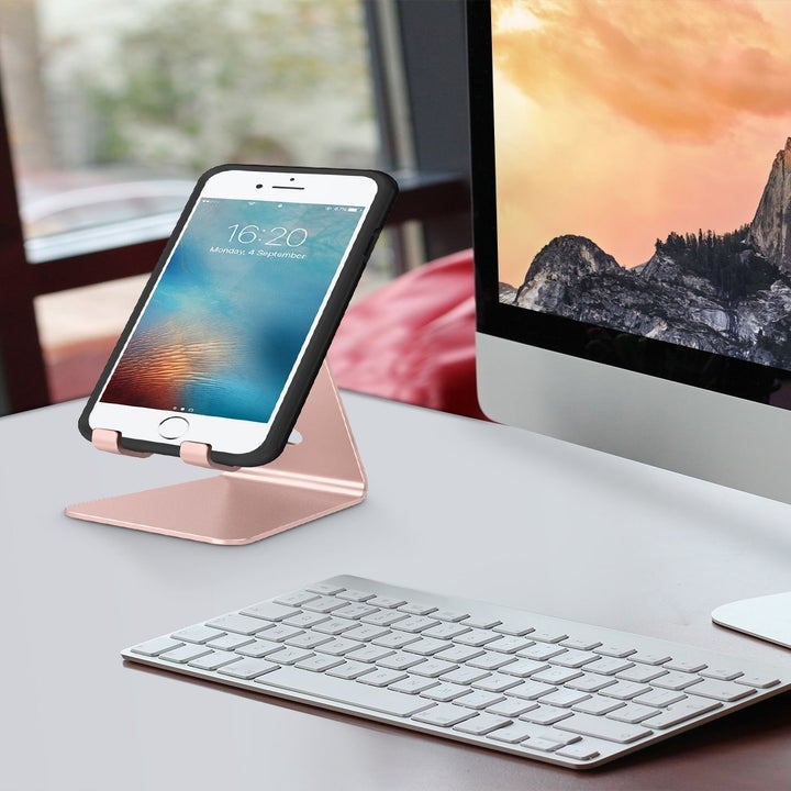 The phone stand next to a computer monitor with a phone on it