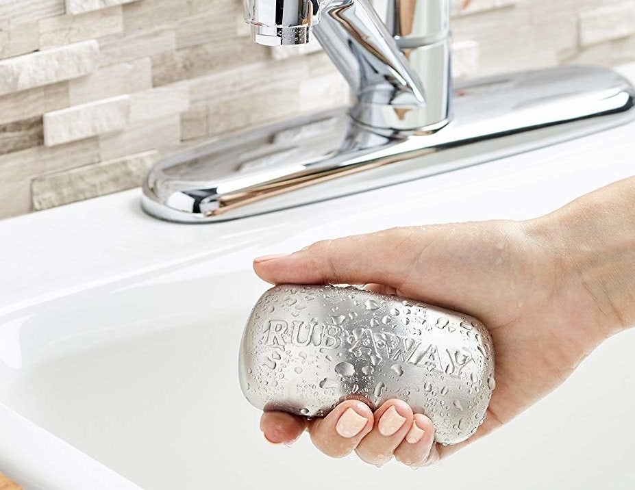 a hand holding the stainless steel bar over a kitchen sink