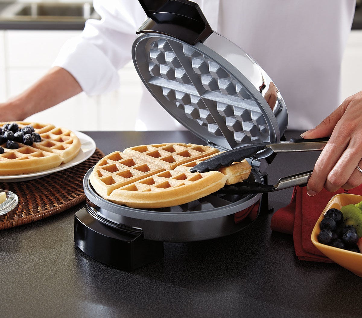 a freshly made waffle being removed from the waffle maker