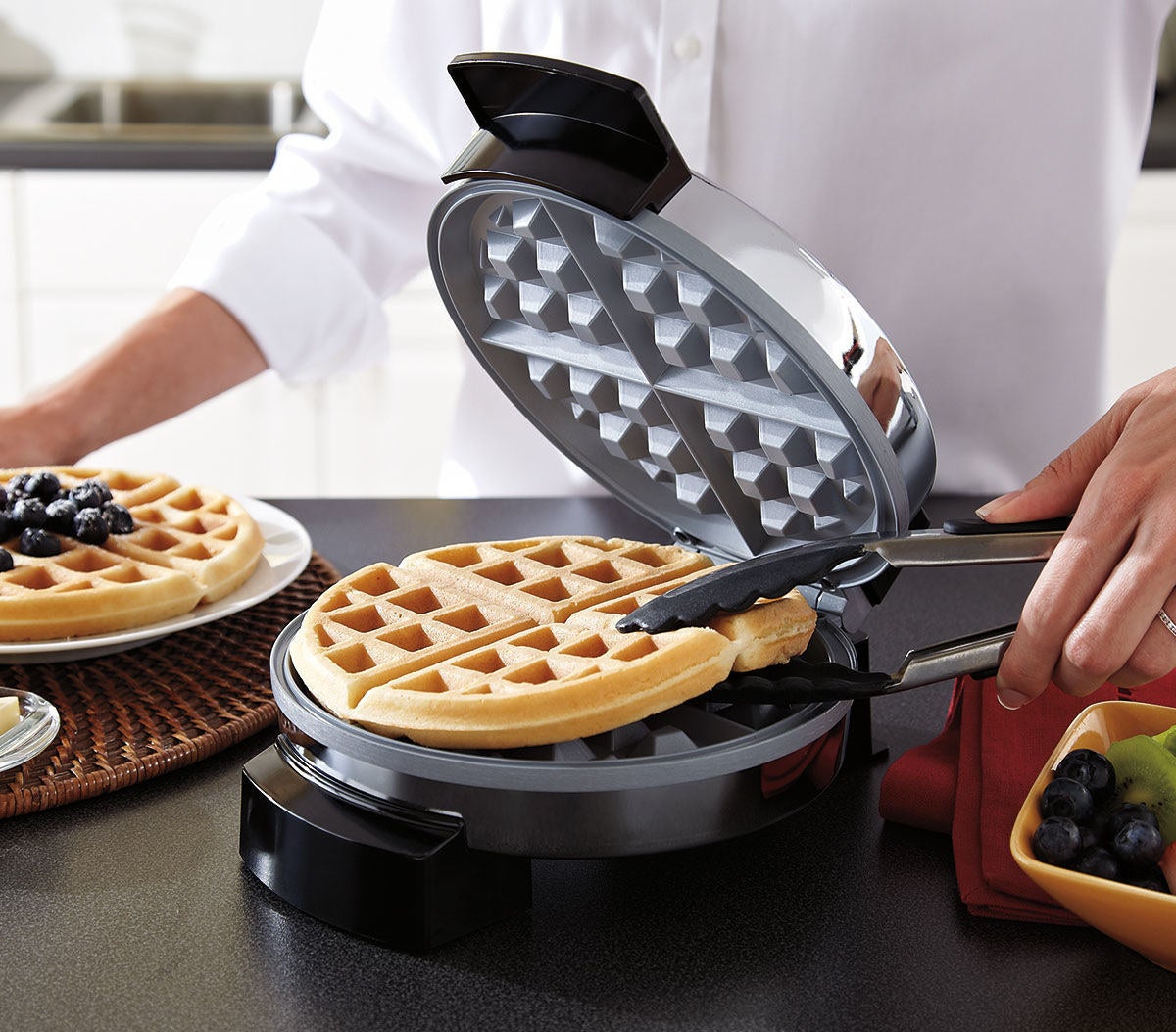 a freshly made waffle being removed from the waffle maker