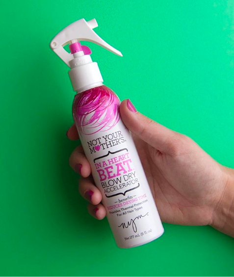 A hand holding a spray bottle of the product