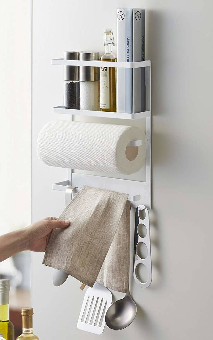 the magnetic kitchen rack holding a roll of paper towels and various cooking utensils