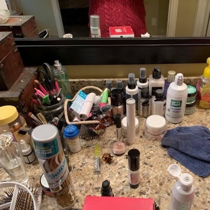 bathroom counter scattered with makeup and bottles
