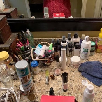 bathroom counter scattered with makeup and bottles