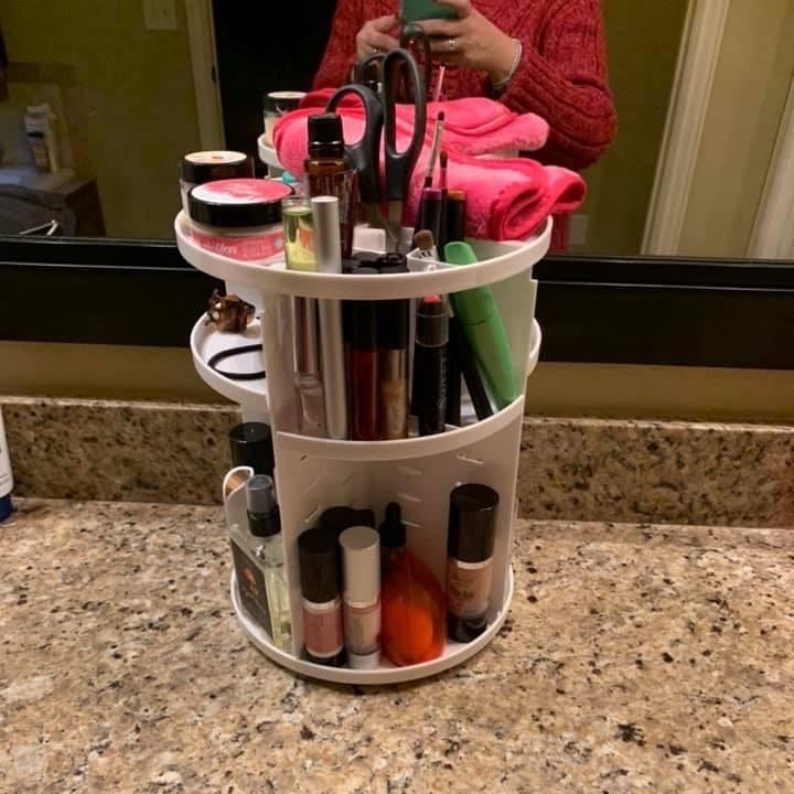 a white cylindrical makeup organizer stacked with neatly with cosmetics