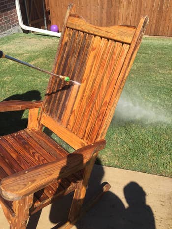 outdoor wooden rocker being pressure washed, half with dark stains, and half where the wood looks like-new