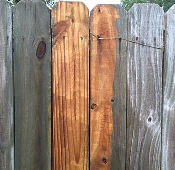 wooden fence that's brown in the middle where it's been pressure washed and gray with residue on either side