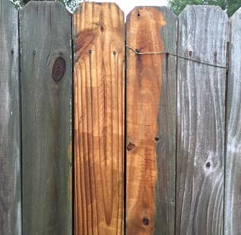 wooden fence that's brown in the middle where it's been pressure washed and gray with residue on either side