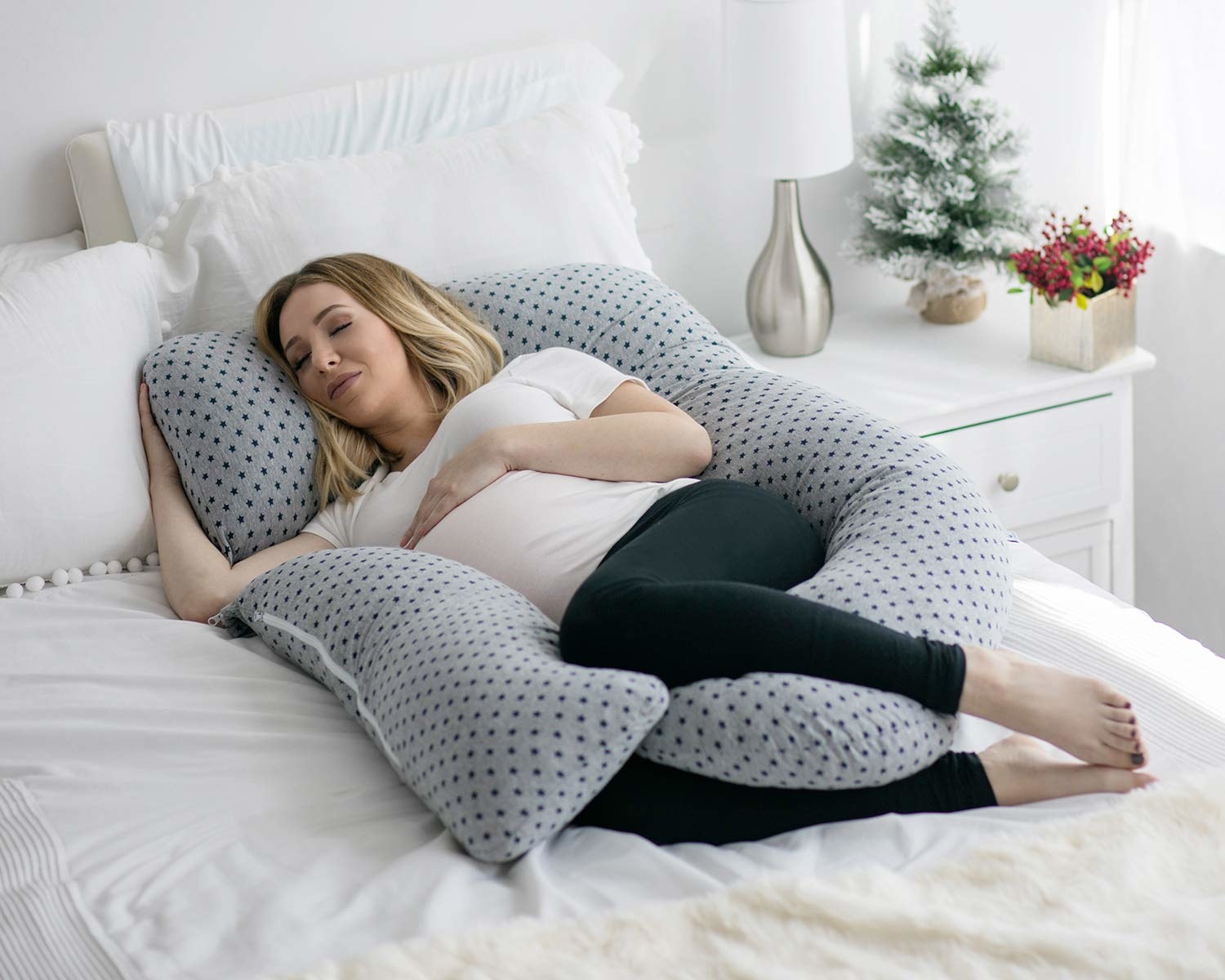 a model curled up with a pregnancy pillow