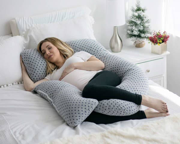 pregnant person cradled in the pillow on a bed