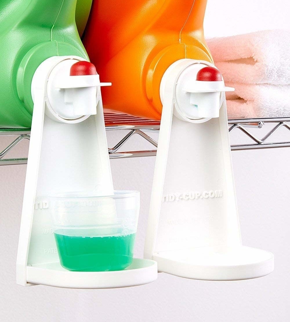 two tidy cups attached to laundry detergent bottle, with one holding a full cup of laundry detergent