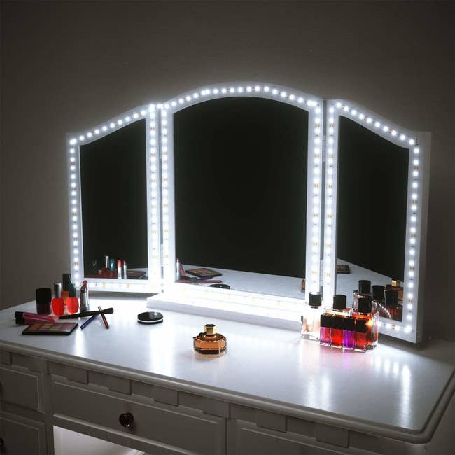 Vanity with a three-section mirror, each with a ring of lights around the outside, illuminating it