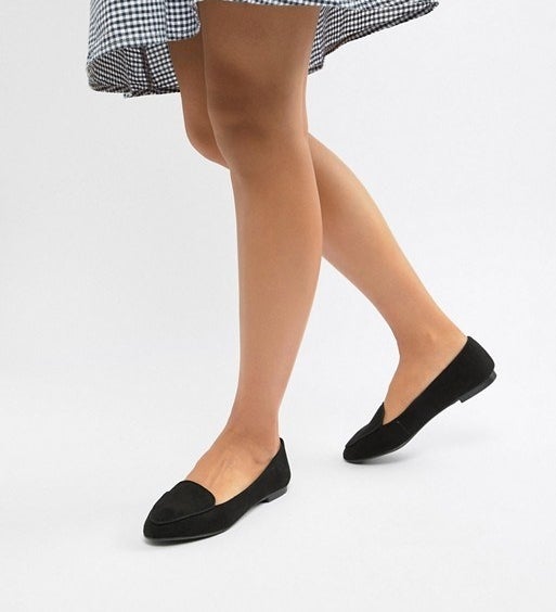 A model wearing the black, round toe, slip-on style loafers 