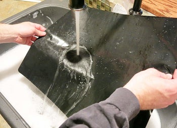 A person washing the liner under a sink