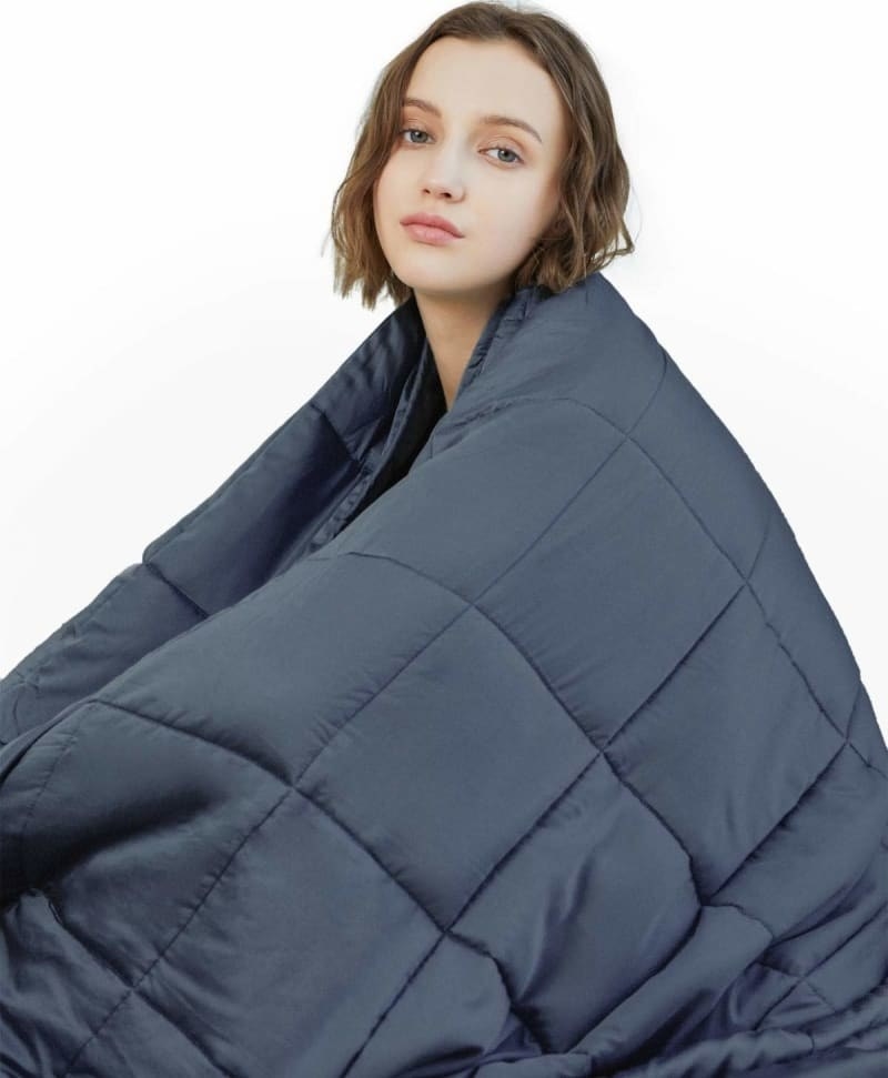 A person with the weighted blanket wrapped around them