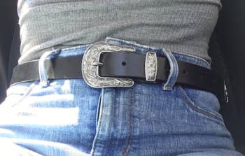 reviewer wearing belt with a gray top and jeans