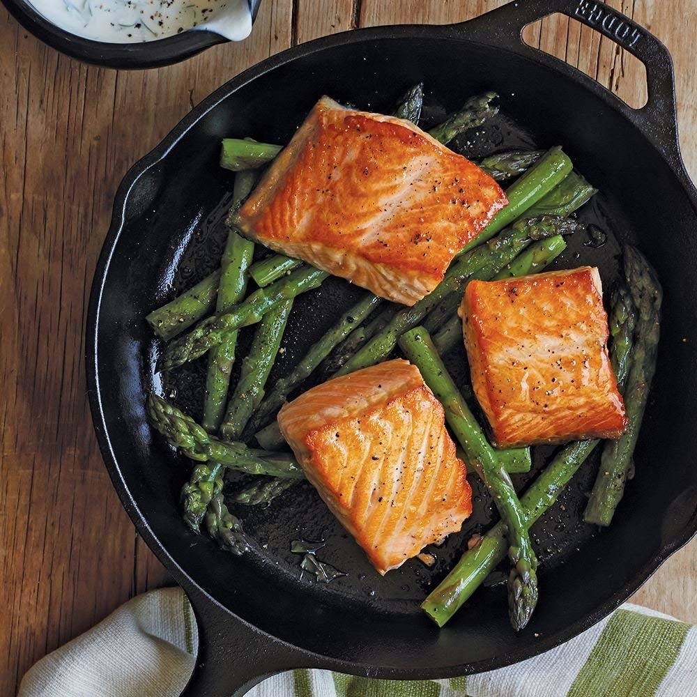 cast iron pan holding salmon and asparagus