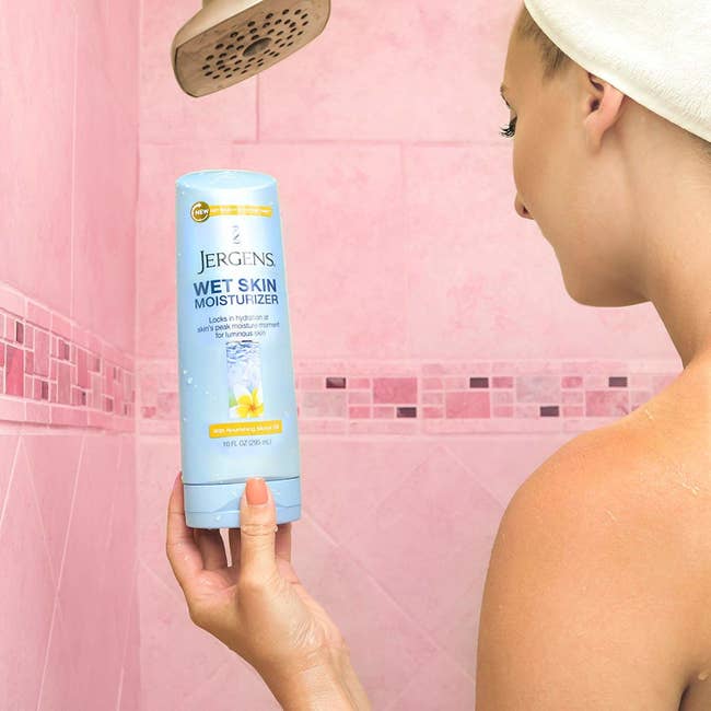 Model holding the bottle of lotion in the shower