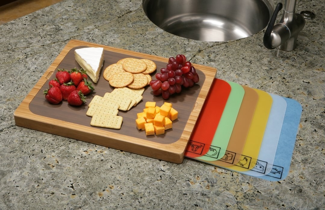 The cutting board and plastic mats, each with a different logo to indicate what kind of food it&#x27;s meant to be used for 