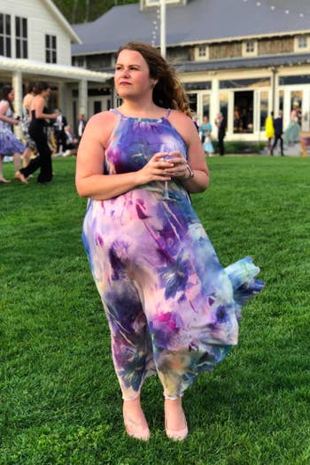 A reviewer wearing the sleeveless dress in an abstract purple print