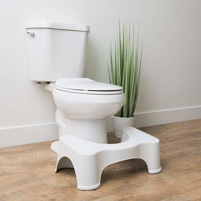 The white Squatty Potty u-shaped stool in front of a toilet