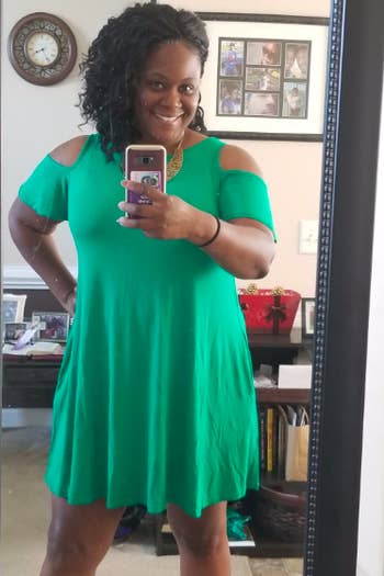 A reviewer wearing the short-sleeve, cold-shoulder dress in green